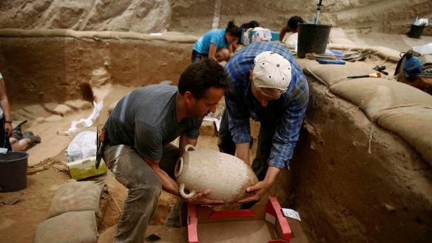 American archaeology students carry a clay jar aft Archäologen entdecken Friedhof der Philister