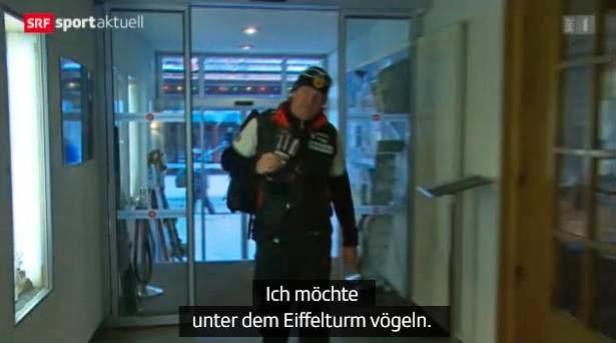 Ein Mann mit Mütze und Weste steht in einem Flur.