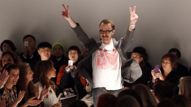 Ein Mann mit Brille und „The Smiths“-T-Shirt jubelt auf dem Laufsteg, umringt von applaudierenden Zuschauern.