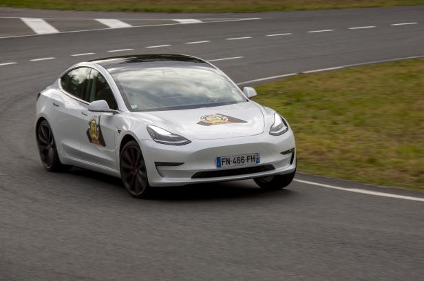 Ein weißes Tesla Model 3 fährt auf einer Rennstrecke.