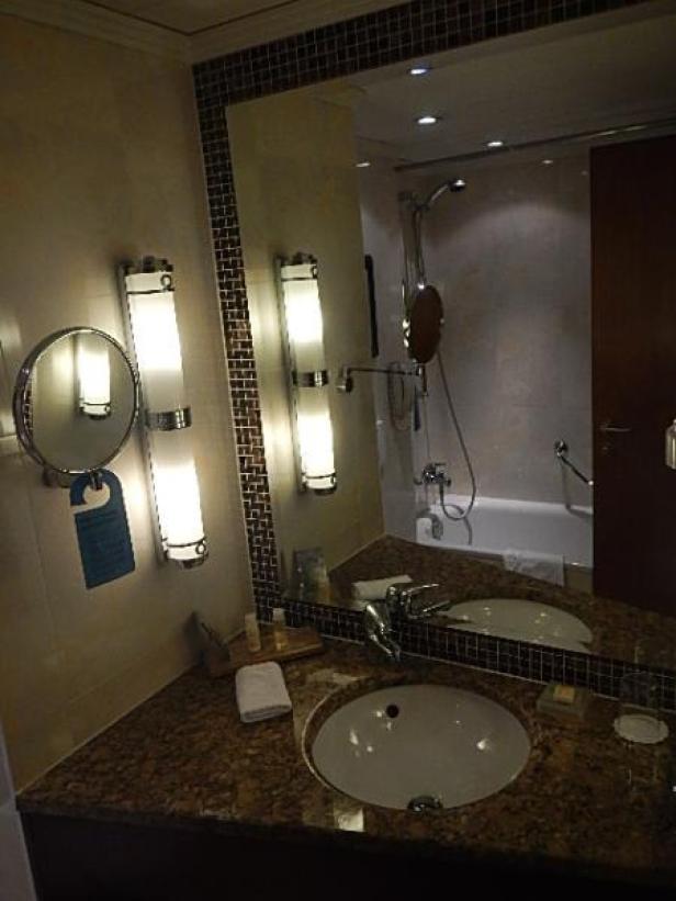 Ein Badezimmer mit Waschbecken, Spiegel und Beleuchtung.