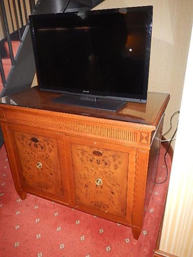 Ein Flachbildfernseher steht auf einem Holzschrank mit zwei Türen.