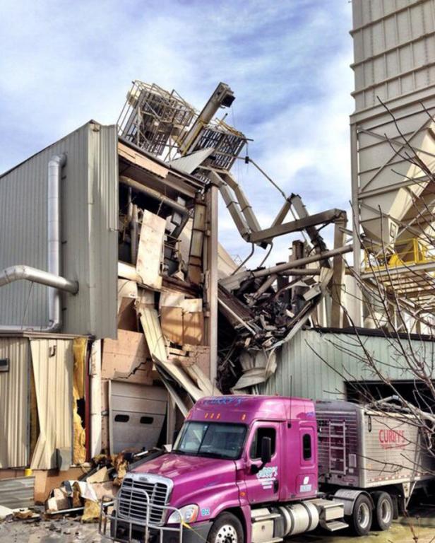 Ein pinkfarbener LKW steht vor einem beschädigten Industriegebäude.