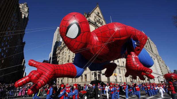Ein riesiger Spider-Man-Ballon schwebt über eine Parade in einer Stadt.