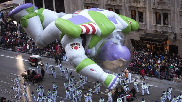Ein riesiger Buzz Lightyear-Ballon schwebt über eine Parade in einer Stadt.