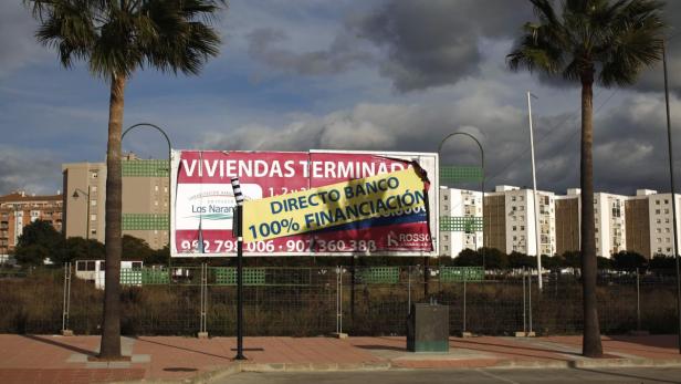 Eine Werbetafel für Wohnungen mit 100% Finanzierung zwischen zwei Palmen.