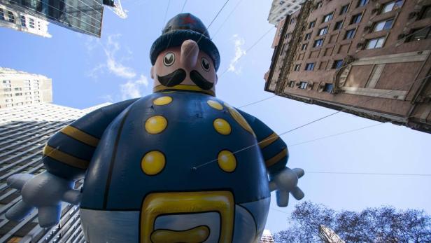 Ein großer, aufblasbarer Polizist schwebt zwischen den New Yorker Wolkenkratzern.