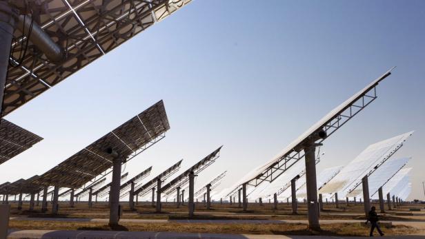 Ein Solarkraftwerk mit vielen Sonnenkollektoren unter einem klaren Himmel.