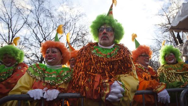 Eine Gruppe von als Clowns verkleideten Menschen steht hinter einer Absperrung.