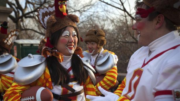 Menschen in Truthahn- und Footballkostümen mit Gesichtsbemalung feiern.