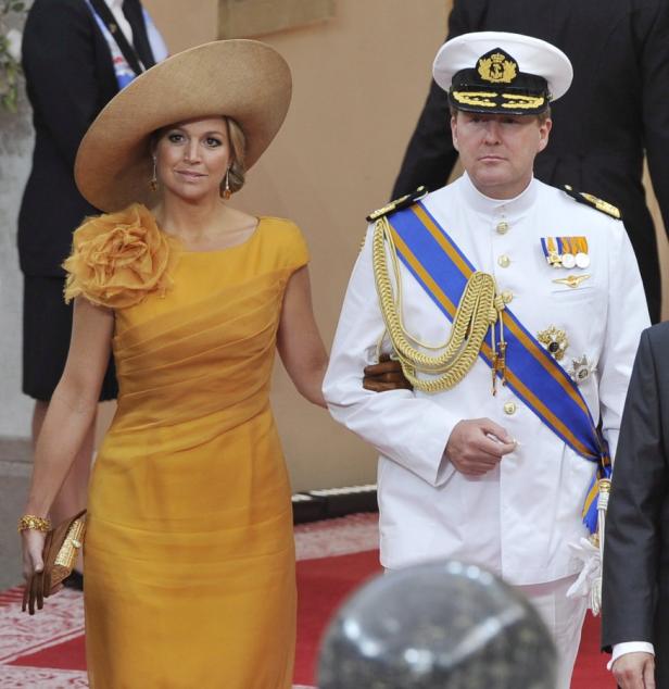 König Willem-Alexander im Marineanzug mit Königin Máxima in einem gelben Kleid.