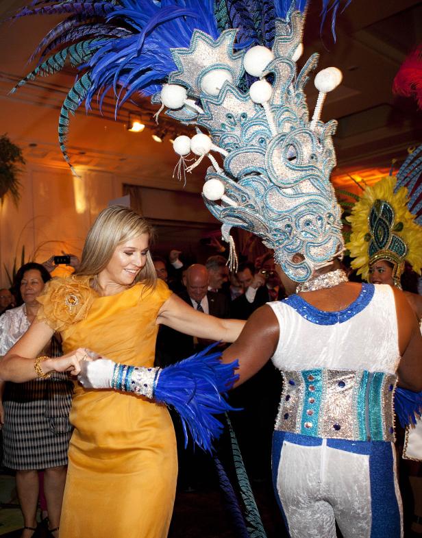 Königin Máxima der Niederlande tanzt mit einem Tänzer in farbenprächtigen Kostümen.