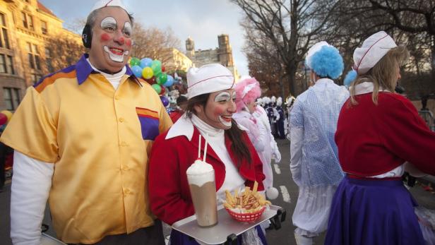 Zwei als Kellner verkleidete Clowns nehmen an einer Parade teil.