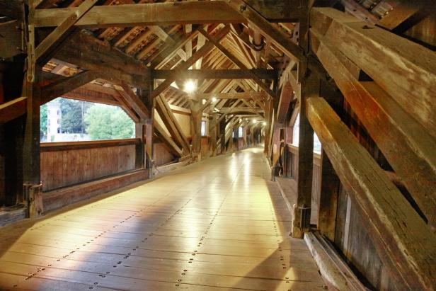 Blick in das Innere einer hölzernen Brücke mit aufwändiger Dachkonstruktion.