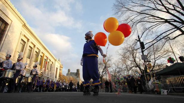 Ein Mann auf Rollschuhen hält Ballons bei einer Parade in der Stadt.
