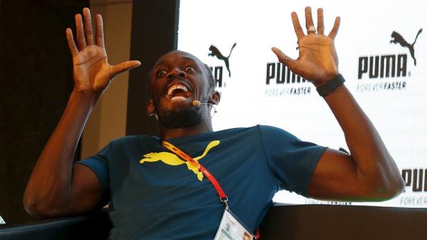 Usain Bolt gestikuliert auf einer Veranstaltung mit erhobenen Händen.