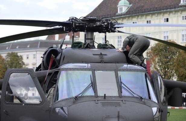 Ein Mann inspiziert einen Militärhubschrauber vor einem Gebäude.