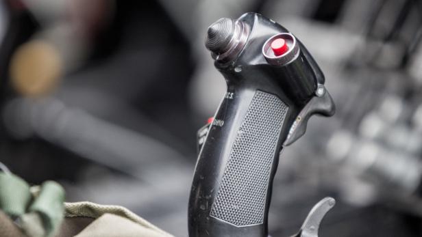 Nahaufnahme des Steuerknüppels eines Flugzeugs mit rotem Knopf.