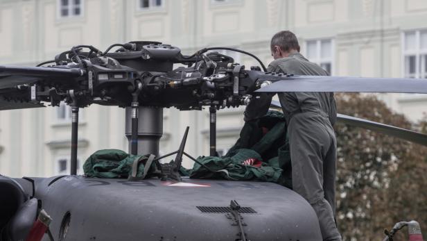 Ein Mann in Arbeitskleidung hantiert am Rotorkopf eines Hubschraubers.