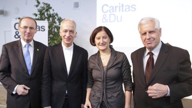 Vier Personen posieren vor einem „Caritas & Du“-Banner.