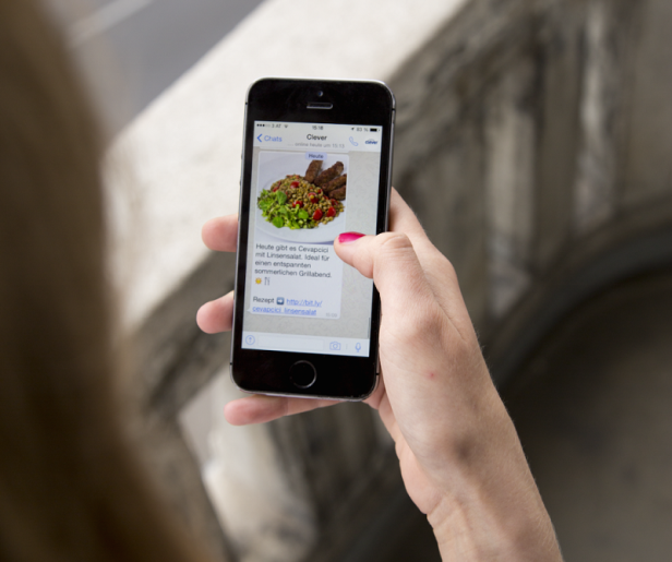 Eine Person betrachtet auf ihrem Smartphone ein Rezept für Cevapcici mit Linsensalat.