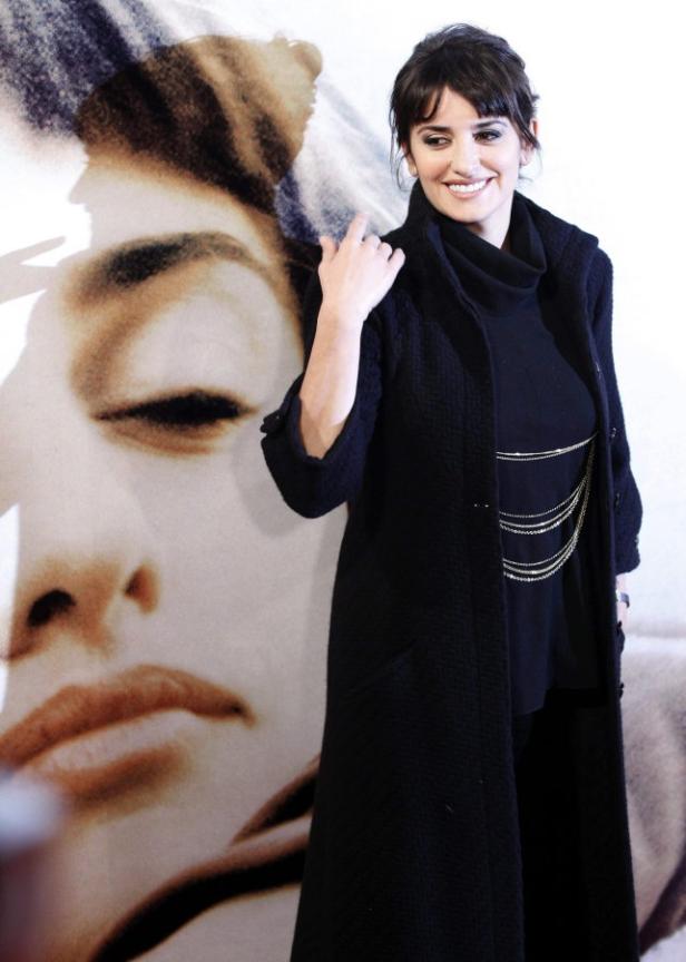 Penélope Cruz posiert vor einem Porträt von Audrey Hepburn.