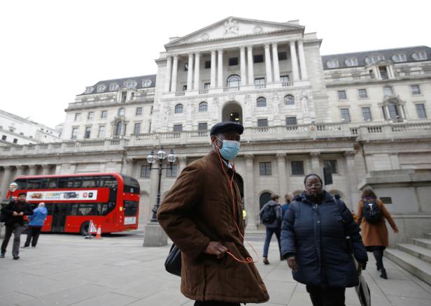 FILE PHOTO: A man, wearing a protective face mask, walks in front of the Bank of England, following an outbreak of the coronavirus, in London
