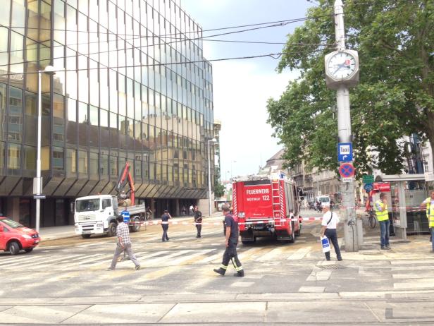 Eine Kreuzung in Wien mit einem Feuerwehrauto und Passanten.
