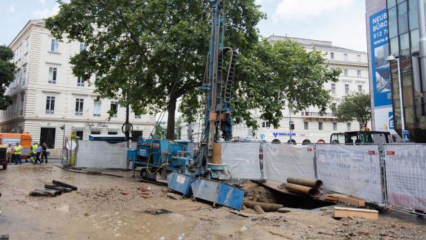 Eine Baustelle in der Stadt mit einem blauen Bohrgerät und Bauarbeitern.