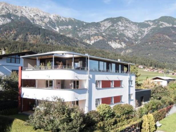 Ein modernes, weißes Gebäude vor einer Bergkulisse.