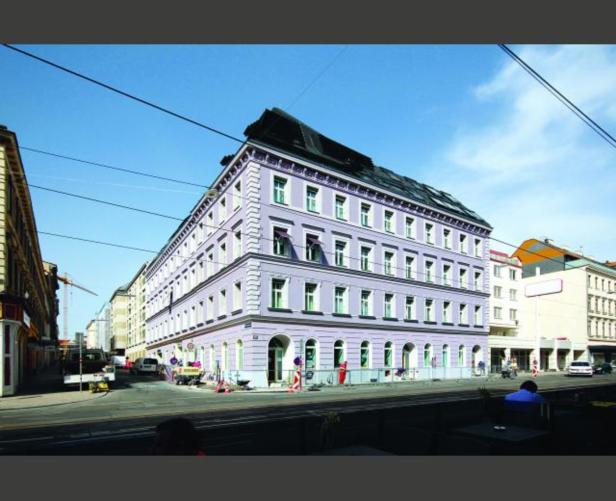 Ein lila Gebäude an einer Straßenecke unter blauem Himmel.