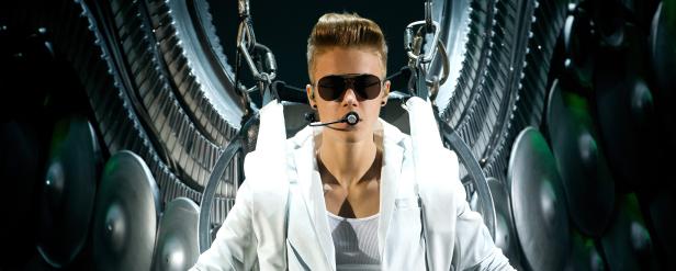 Justin Bieber sitzt in einem futuristischen Stuhl mit Klaviertasten und Becken im Hintergrund.