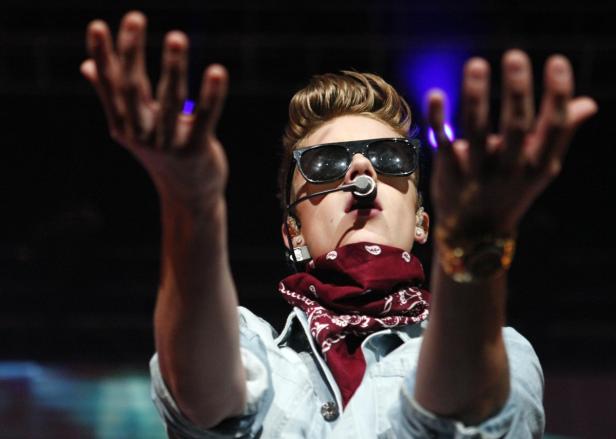 Justin Bieber tritt mit Sonnenbrille und rotem Halstuch auf einer Bühne auf.