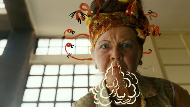 Eine Frau mit einem Turban, der mit animierten Flamingos geschmückt ist, scheint Dampf aus ihrem Mund zu blasen.