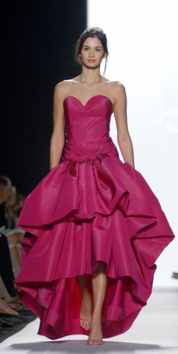 Eine Frau präsentiert ein trägerloses, pinkfarbenes Kleid mit voluminösem Rock auf dem Laufsteg.