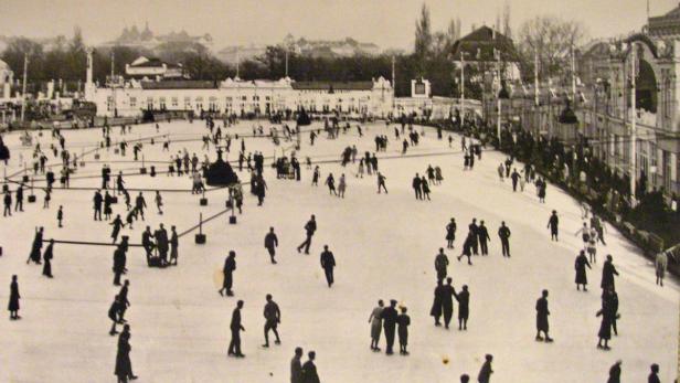 Eine große Menschenmenge läuft auf einer Eisbahn vor historischen Gebäuden Schlittschuh.