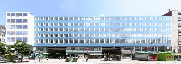 Ein blaues Bürogebäude mit vielen Fenstern über einer Ladenpassage.