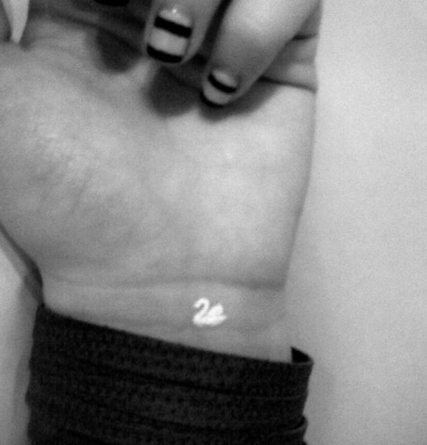 Auf dem Handgelenk einer Person befindet sich ein kleines, weißes Schwan-Tattoo.