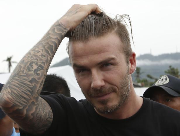 Former England soccer captain Beckham touches his hair as he walks back to his vehicle after visiting an evacuation centre in Tacloban city