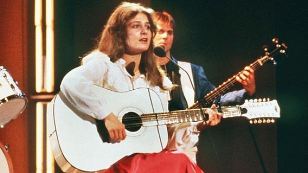 Eine Frau singt und spielt Gitarre, begleitet von einem Mann mit einer zwölfsaitigen Gitarre.