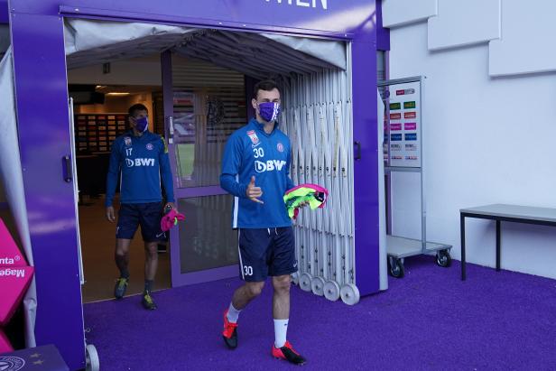 Zwei Fußballspieler von Austria Wien betreten mit Masken das Feld.