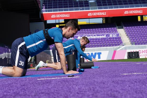 Fußballspieler dehnen sich mit Faszienrollen auf dem Trainingsplatz.