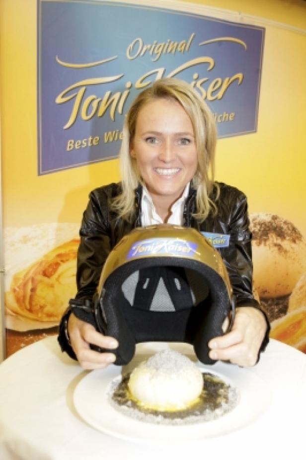 Eine Frau präsentiert einen Helm und einen Kaiserschmarrn von „Toni Kaiser“.
