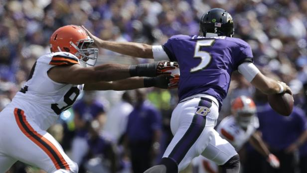 Ein Footballspieler der Cleveland Browns greift einen Quarterback der Baltimore Ravens an.