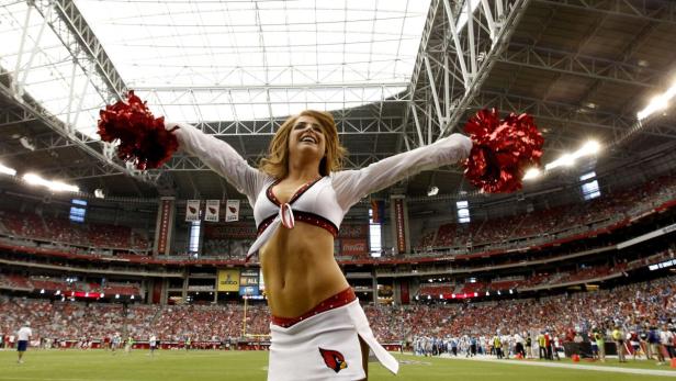 Eine Cheerleaderin der Arizona Cardinals feuert ihr Team in einem vollbesetzten Stadion an.
