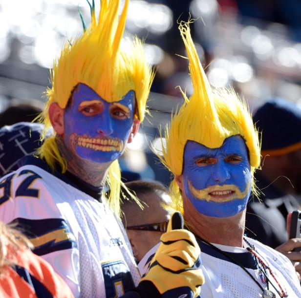 Zwei Fans der Los Angeles Chargers mit blau bemalten Gesichtern und gelben Perücken feuern ihr Team an.