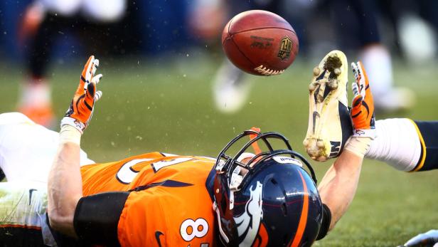 Ein American-Football-Spieler liegt auf dem Rücken und versucht, einen Ball zu fangen.