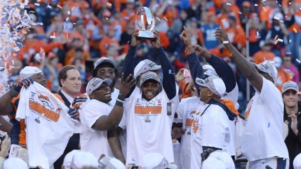 Footballspieler der Denver Broncos feiern ihren Sieg mit einer Trophäe und Konfetti.