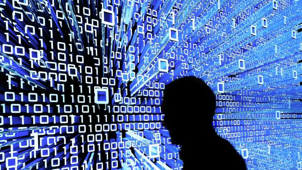 Die Silhouette einer Person vor einem Hintergrund aus binärem Code in Blau und Weiß.