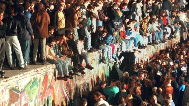 Menschen feiern auf der Berliner Mauer.
